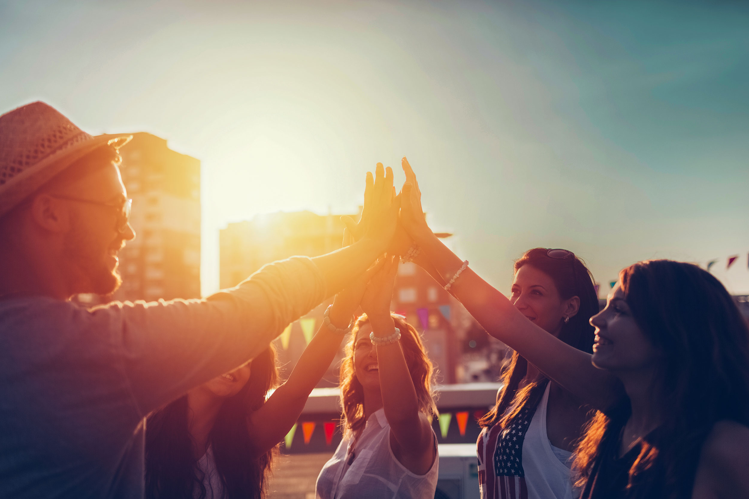 Schmetterling International stimmungsvolles Headerbild, Menschen geben sich High Five bei untergehender Sonne